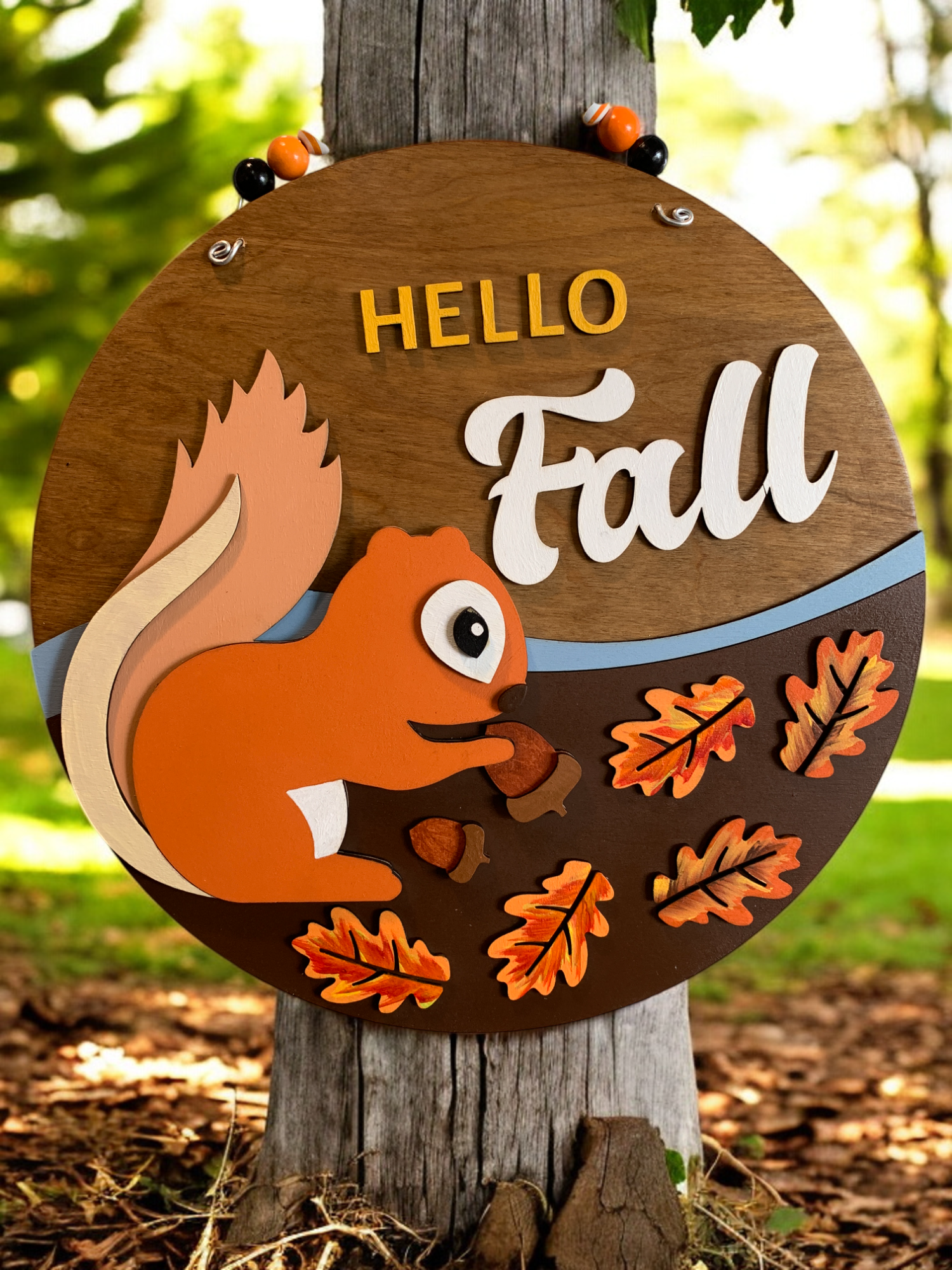 a 3D wooden round sign with squirrel and hello fall 