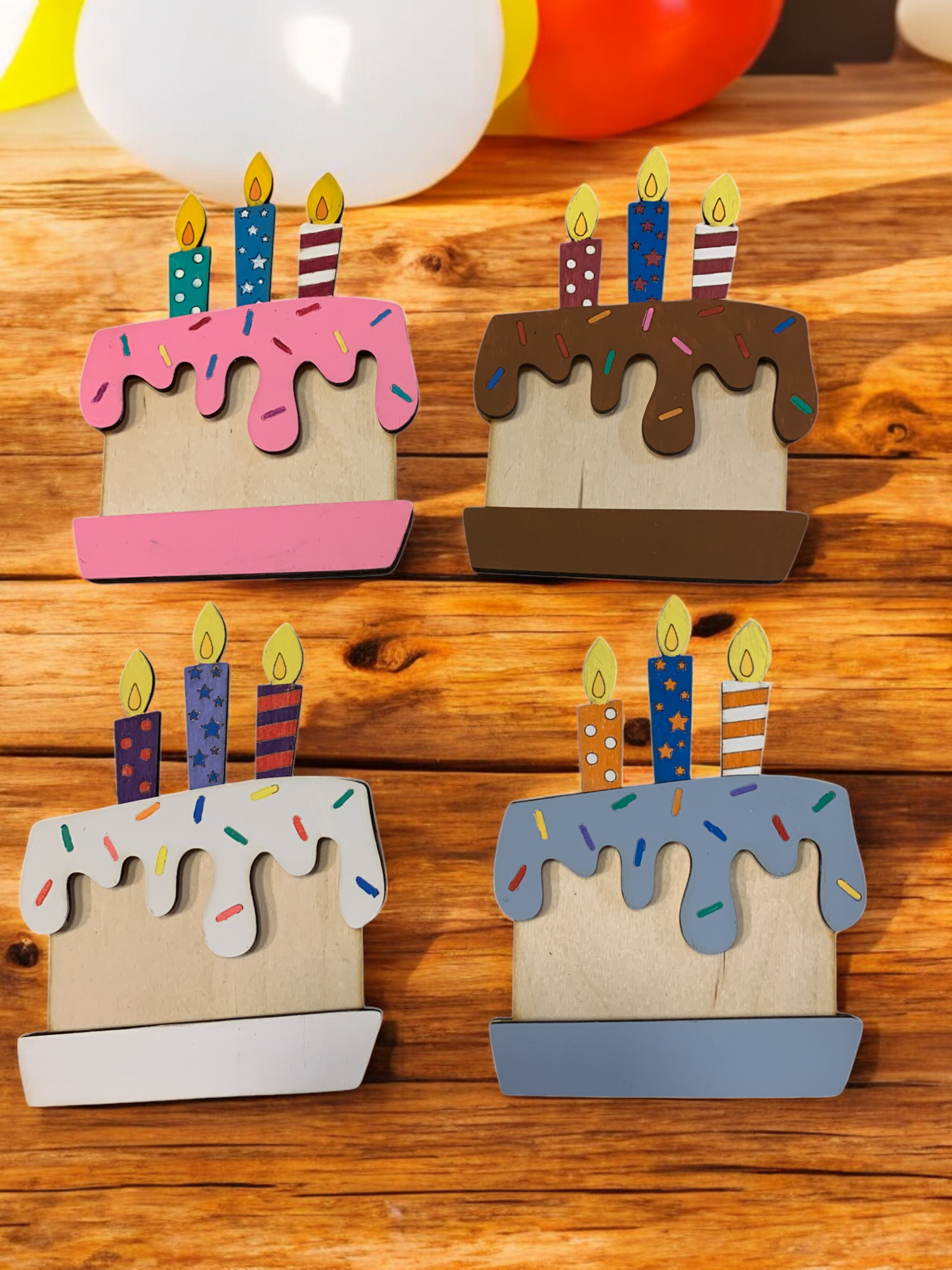 Handmade wooden birthday cake gift card holders with candles and colorful frosting — gift card slots into the layers, displayed on a rustic wood table