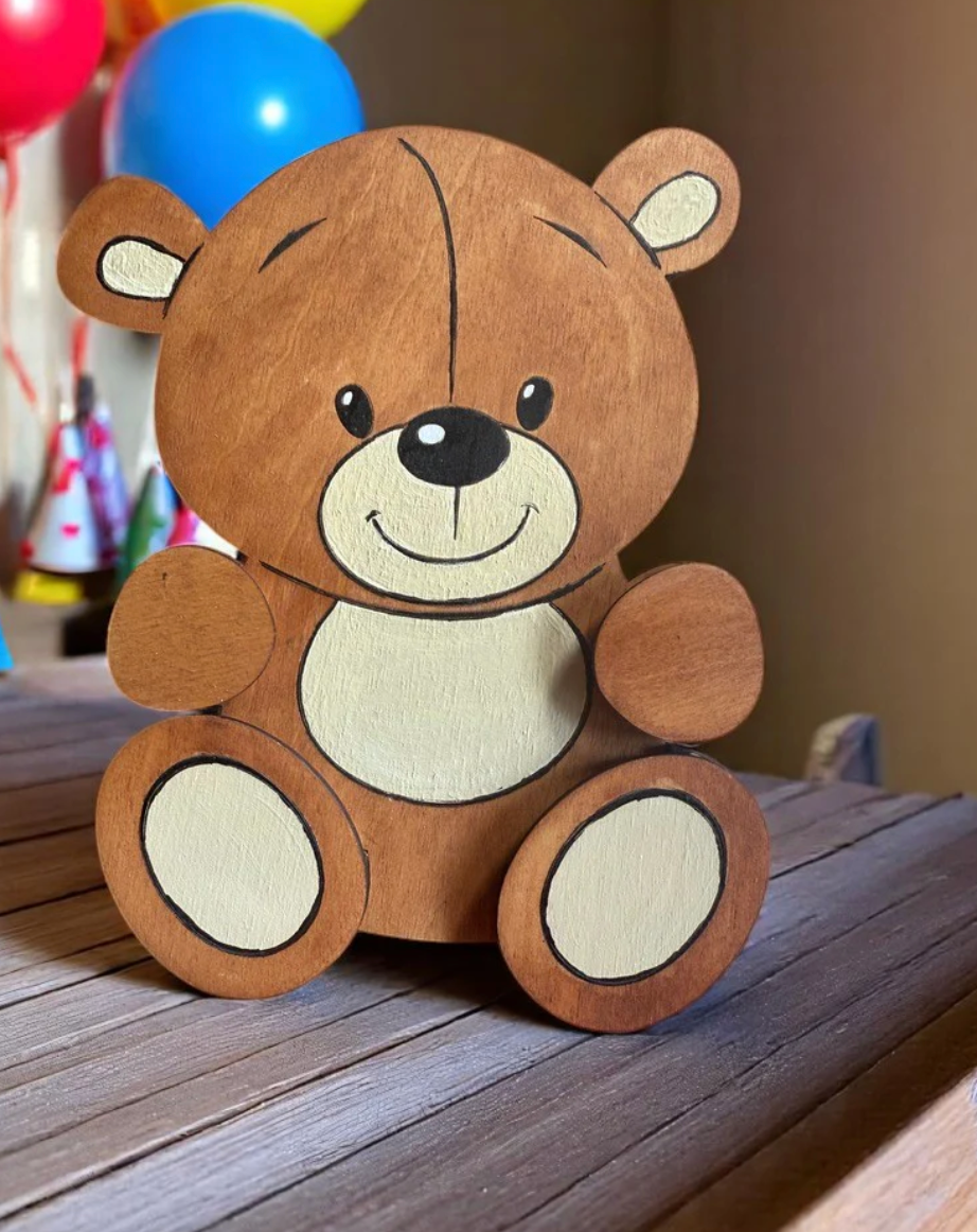 Handmade wooden teddy bear gift card holder with brown and cream design, displayed on a rustic wood surface with colorful balloons in the background — baby shower gift idea
