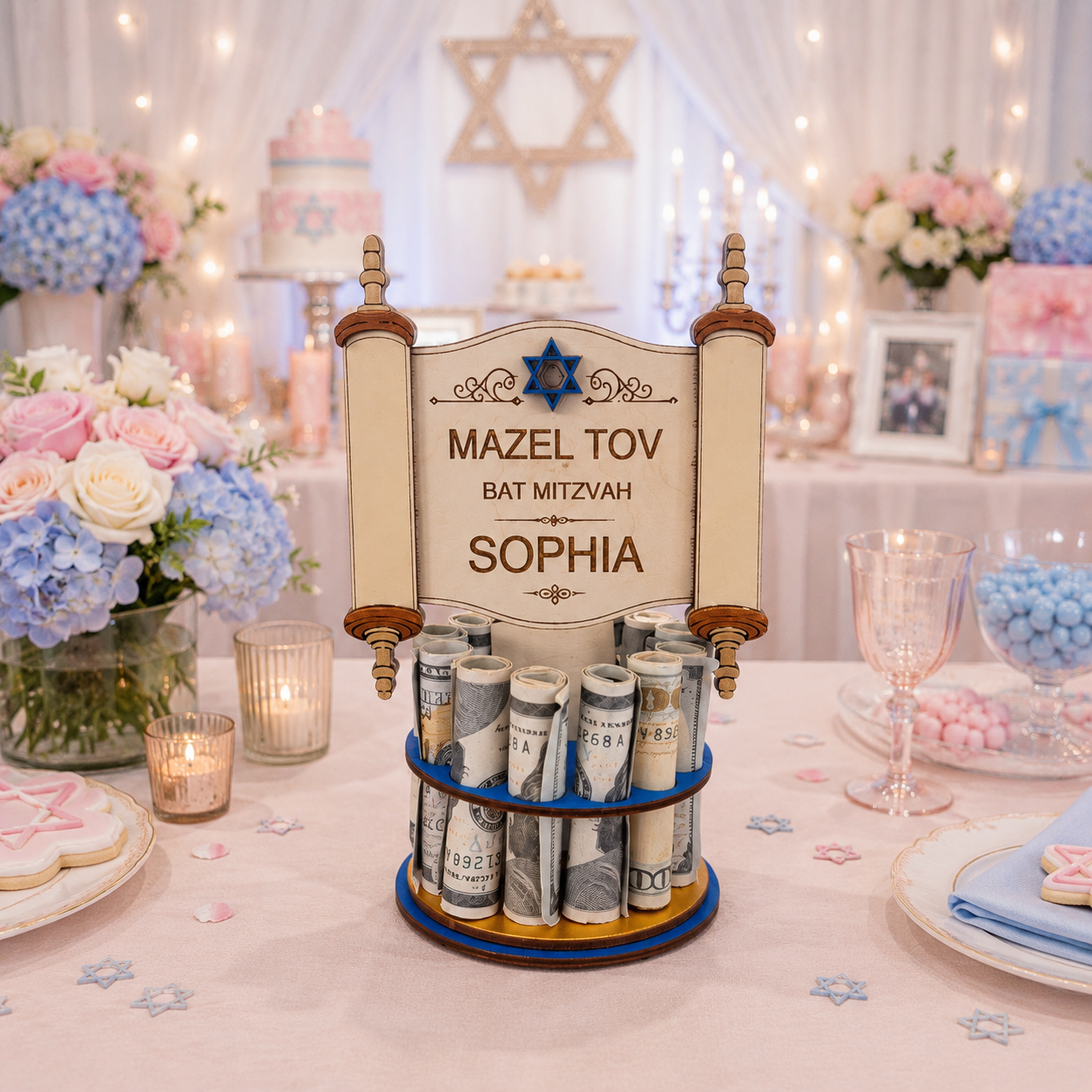 Premium handmade wood Torah scroll Bar Mitzvah money tree with detailed open scroll design, Star of David, and personalized text reading "Mazel Tov Bat Mitzvah Sophia," on a single-tiered blue base holding 13 rolled bills, styled on a pink Bat Mitzvah celebration table with blue hydrangeas and pink roses