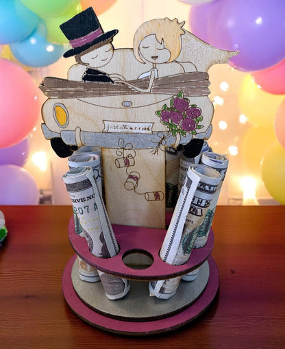 Handmade wood just married car money tree topped with a hand-drawn couple driving off in their wedding car with bouquet and "Just Married" banner, displaying rolled bills