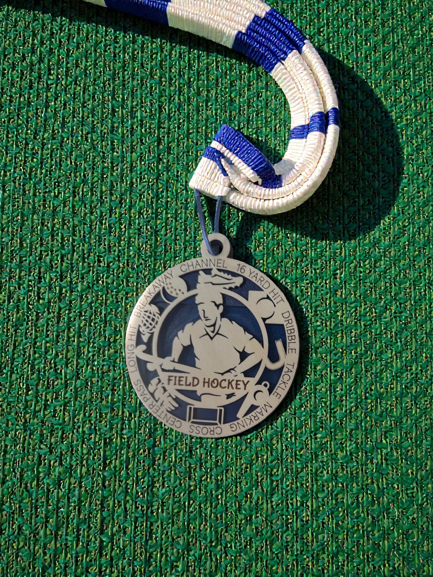 Medal with 'Field Hockey' design on a green textured surface