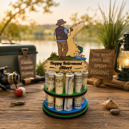 Handmade wood fishing money tree holding rolled bills, topped with a hand-painted fisherman and a personalized "Happy Retirement" sign, styled on a rustic table with a tackle box, reel, and lantern by a lake at sunset