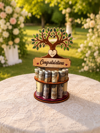 Premium handmade wood tree of life money tree with hand-painted green leaves, heart-shaped trunk cutout personalized with "1st 2026," and Congratulations banner, displayed on a single-tiered base holding 12 rolled bills, styled outdoors with a white rose garden and wedding arch in the background