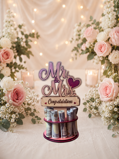 Premium handmade wood Mr. & Mrs. wedding money tree with laser-cut script lettering and personalized name banner reading "Congratulations" displayed on a two-tiered pink circular base holding 12 rolled bills, surrounded by pink roses and candlelight