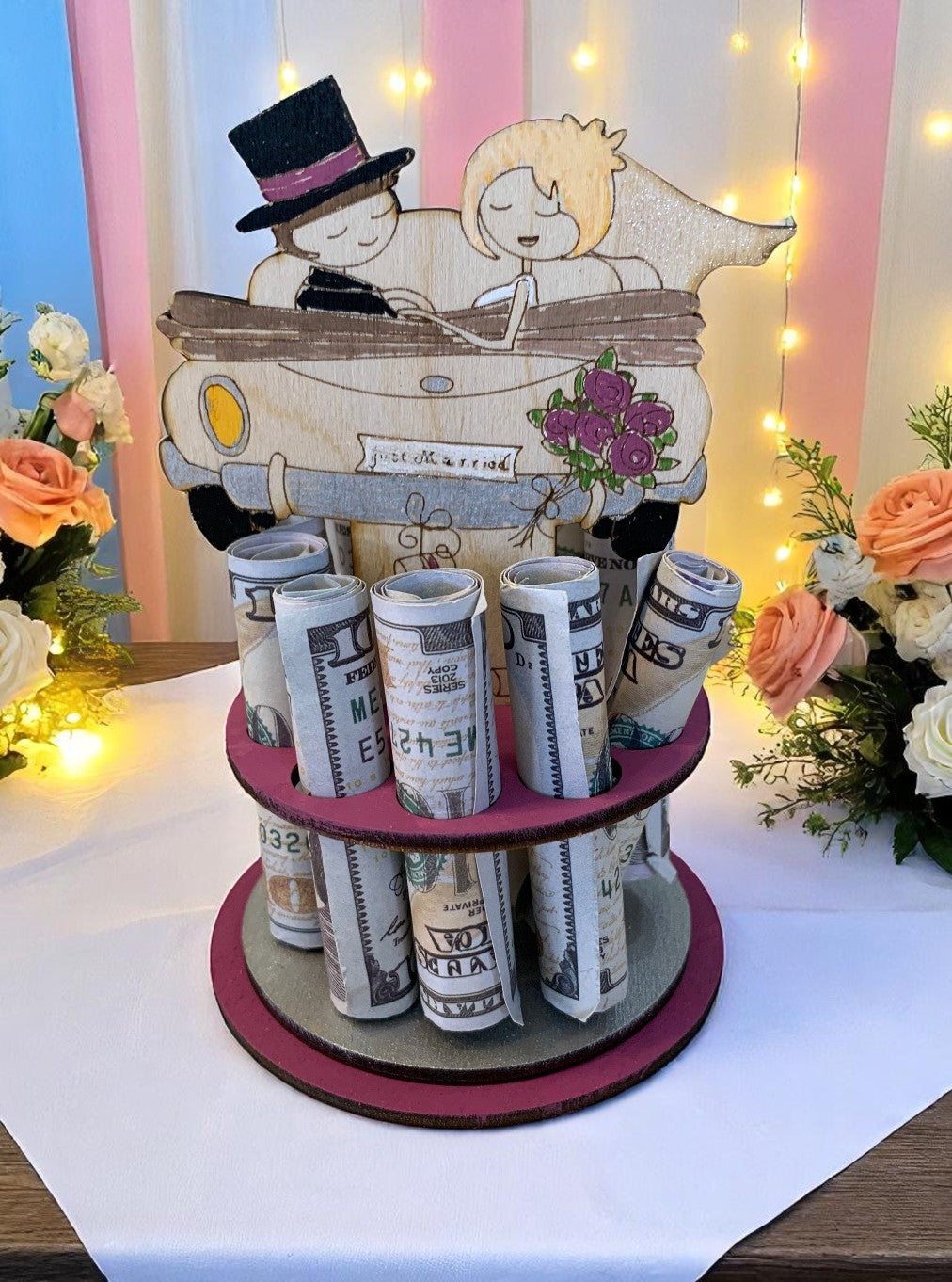Handmade wood just married car money tree with the newlywed couple design, rolled bills displayed in rows, styled with peach and white roses