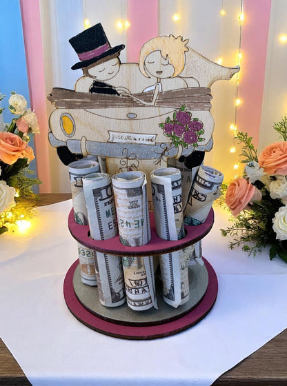 Handmade wood just married car money tree with the newlywed couple design, rolled bills displayed in rows, styled with peach and white roses